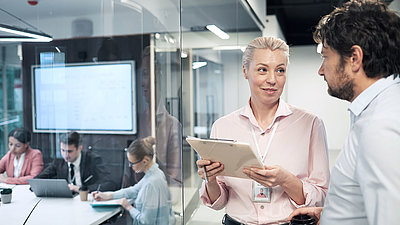 Individuelle Lösung als Plattform-Betreiber Zwei Mitarbeitende stehen im Büro und tauschen sich über Ideen aus