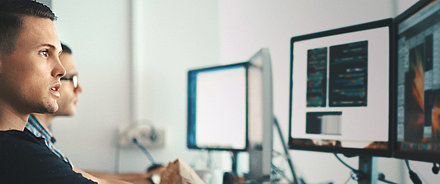 LANCOM Betriebssysteme Junger IT-Mitarbeiter vor PC-Bildschirm