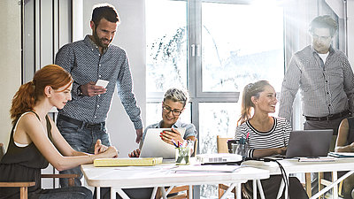 Personen diskutieren an einem Schreibtisch